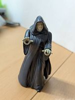 Front view of Emperor Palpatine figure showing face, hood, and extended hand with lighting mechanism.