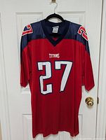 Front of the red Tennessee Titans football jersey with number 27 and 'TITANS' text on chest, navy blue shoulders and red mesh fabric body.