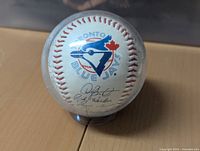 Front side of the baseball showing the Toronto Blue Jays logo and some autographs beneath it.