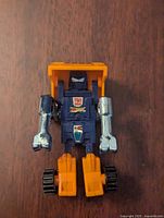 Front view of the robot mode showing yellow and blue colors, chrome silver arms, and Autobot logo on chest.