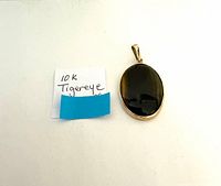 Photo of the tiger's eye pendant on a white background with a note reading "10 K Tigereye".