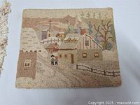 Front view of one hooked rug showing village houses and fenced lane