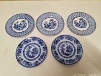 Five antique British Flow Blue bread plates showing various blue transferware patterns on white porcelain.