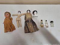 Full view of all dolls and glass figurines on white surface, showing arrangement and relative sizes.