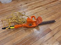 View of the hedge trimmer showing the blade and body with power cord coiled nearby.
