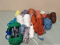Overview of multiple crafting cords and yarns in various colors and sizes laid on a surface.