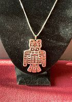 Front of Thunderbird pendant on necklace displayed on a black velvet bust showing detailed tribal designs in silver.