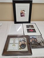 Collection of various photo frames including black rectangular with white mat, white rectangular, and black graduation-themed frame.