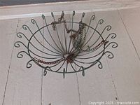 Full wide shot of the round green metal hanging plant holder with spiral wire design and chains attached on a white background.