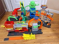 Wide shot of Hot Wheels playset showing multiple track sections, launcher mechanisms, monster and alien designs, and yellow tow truck.