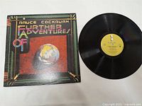 Vinyl record Further Adventures of Bruce Cockburn with yellow True North label and original album cover with globe artwork.