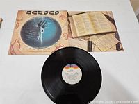 Vinyl record album along with cover and inner sleeve shown on white surface.