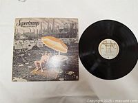 Photo of Supertramp Crisis? What Crisis? album cover and vinyl record showing the cover art and the black vinyl with label.