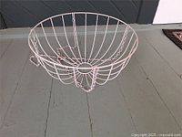 Top side view of white metal hanging plant holder showing circular wire frame and attached chains.