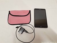 Samsung Galaxy Tab 4 tablet, pink carrying case, and charger laid out for display.