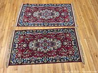 Two rectangular scatter mats placed side by side on wooden floor, showing front design and fringe at edges.
