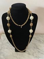 Front view of the gold tone chain necklace with large faux baroque pearls and decorative filigree beads, displayed on a black bust.