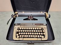 Smith-Corona Classic 12 electric typewriter in open black hard carrying case with keyboard and paper roller visible.
