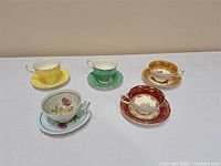 Five vintage Paragon teacup and saucer sets arranged on table showing variety of colors and styles.