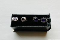 Top view of both pairs of amethyst earrings showing color and setting differences.