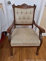 Front view of wooden Victorian occasional chair showing carved crest on backrest and patterned upholstery.
