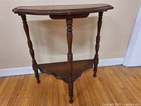 Side view of the vintage demilune table showing the turned legs and lower shelf.