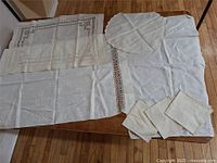 Overview of all linen pieces spread on table showing the large and round cloths with napkins on top