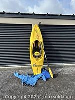 Yellow Dagger kayak upright with helmet in cockpit, paddle and paddling jacket on ground