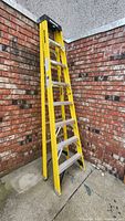 Full view of 8ft yellow fiberglass step ladder with aluminum steps and Maximum branding on side rails.