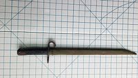 Full-length view of bayonet in scabbard on grid background
