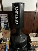 Full view of Century Wave Master punching bag with base and boxes around it