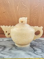 Front view of carved stone dragon teapot on marble surface