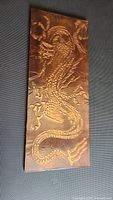 Full view of the copper artwork showing the entire dragon design on a rectangular panel.
