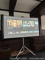 Projection screen set up on tripod stand displaying YouTube video interface, indicating screen and stand are functional and in working condition.