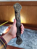 Front view held in hand showing full length and carved motifs