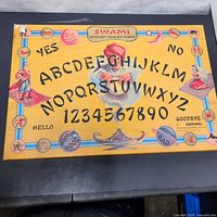 Top view photo of the Swami Mystery Talking Board showing the full board with alphabet, numbers, illustrations, and text.