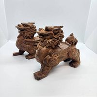 Pair of wood carved Kirin statues angled side view showing detailed craftsmanship and texture