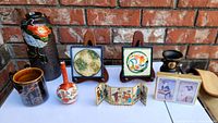 Seven Japanese vintage items arranged showing porcelain vases, hand painted coasters, miniature screen, and playing cards