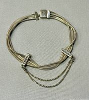 Top-down view of the two-strand Pandora bracelet laid flat on a grey surface, clearly showing the multiple silver strands, Pandora engraved clasps, and safety chain.
