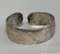 Front view of silver cuff bangle showing detailed Haida art engraving.