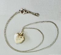 Heart-shaped sterling silver locket necklace laid flat showing chain and pendant.