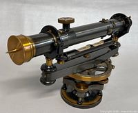 Front angle of the Keuffel & Esser transit level scope showing brass objective lens and spirit level bubble mounted under the horizontal telescope tube.