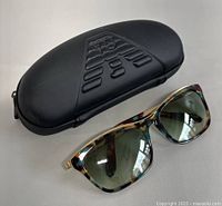 Miu Miu sunglasses resting on black Emporio Armani case showing frame and lenses detail