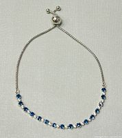 Full view of the Pandora bracelet showing the alternating blue and clear stones on a silver-tone chain with an adjustable slider clasp.