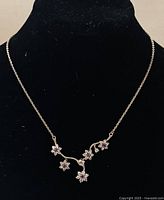 Front view of the Pandora floral necklace displayed on a black velvet bust showing the five flowers with purple and clear stones.