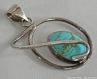 Front view of signed 925 silver and turquoise pendant, showing the turquoise cabochon and silver wire design.
