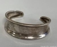 Front view of vintage silver open cuff bangle showing the flared shape and smooth surface.