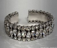 Front view of the open cuff bangle showing two rows of clear rhinestones arranged in round and pear shapes on sterling silver.