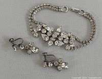 Photo showing the full set of vintage Jay Flex rhinestone jewelry including bracelet and two earrings on a gray background.
