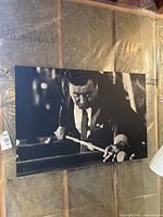Front view of first black and white board-mounted print showing a man leaning over a pool table